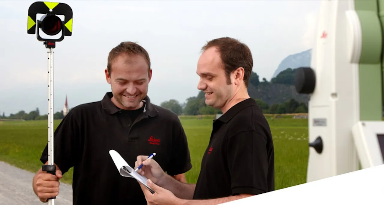 Zwei Männer stehen im Freien mit Vermessungsgeräten